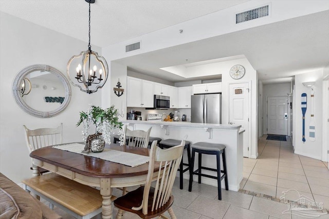 tiled dining room with a chandelier and a textured ceiling