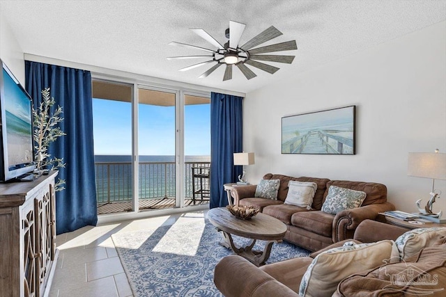 living room with a water view, light tile patterned floors, a textured ceiling, and a wall of windows