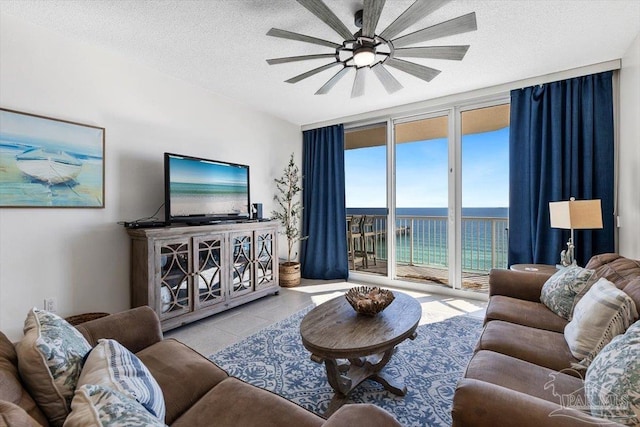 tiled living room featuring ceiling fan, floor to ceiling windows, and a textured ceiling