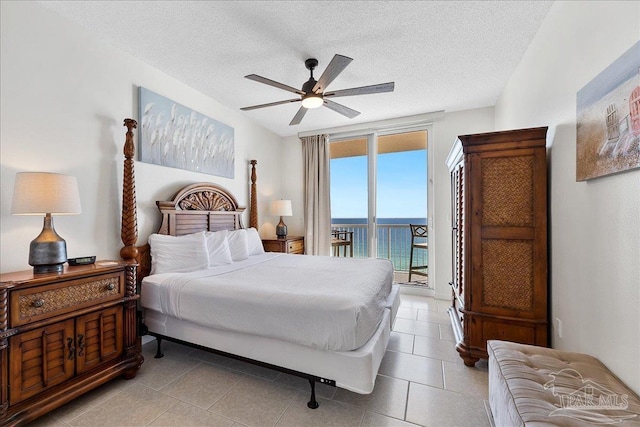 bedroom with access to outside, light tile patterned floors, ceiling fan, a water view, and a textured ceiling