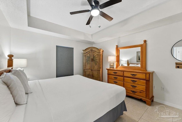 tiled bedroom with a raised ceiling, a textured ceiling, and ceiling fan