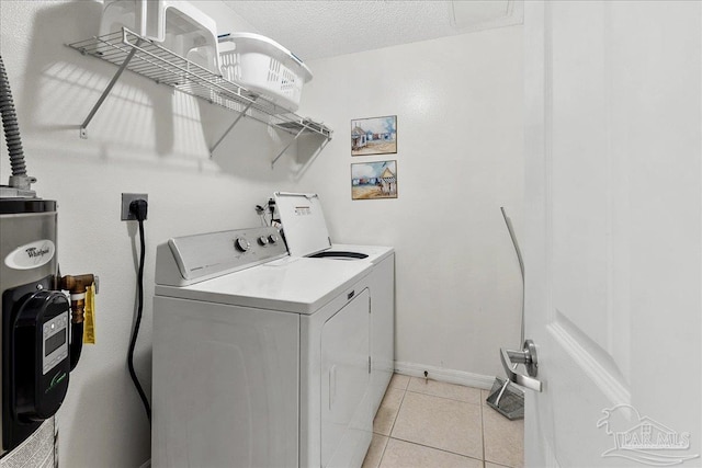 washroom featuring water heater, washing machine and dryer, a textured ceiling, and light tile patterned floors