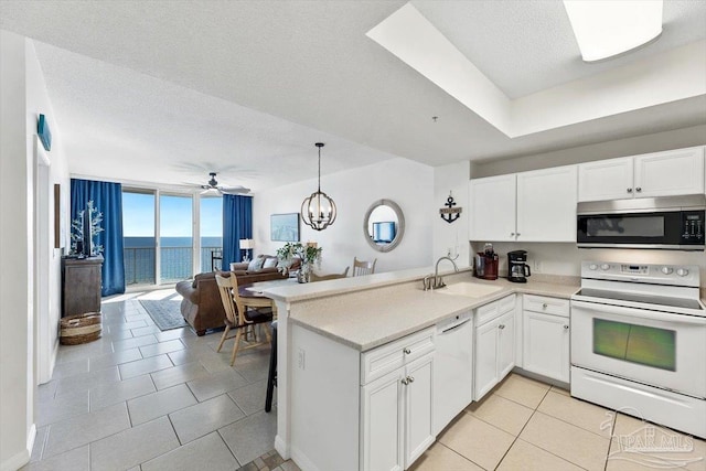 kitchen featuring sink, white appliances, a water view, white cabinets, and kitchen peninsula