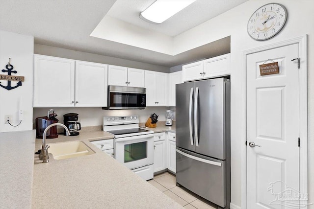 kitchen featuring appliances with stainless steel finishes, sink, light tile patterned floors, and white cabinets