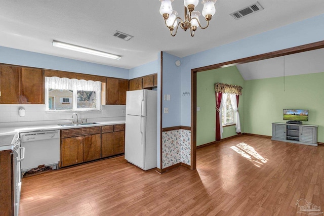 kitchen with white appliances, light hardwood / wood-style floors, a wealth of natural light, and sink