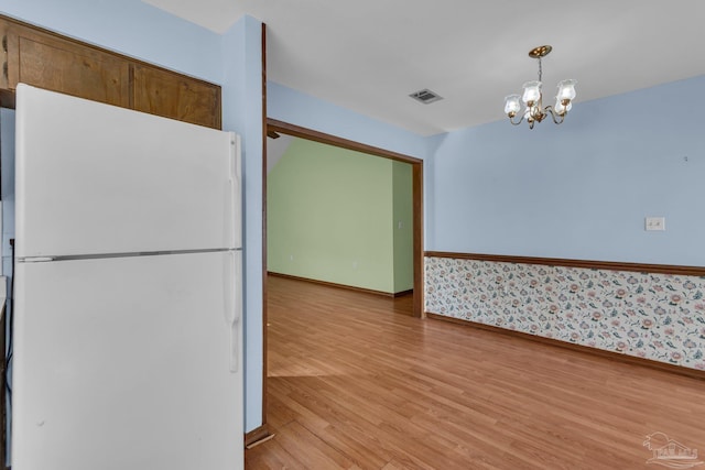 kitchen featuring white fridge, hanging light fixtures, an inviting chandelier, and light wood-type flooring