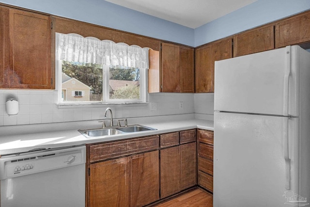 kitchen with sink, white appliances, tasteful backsplash, and light hardwood / wood-style flooring