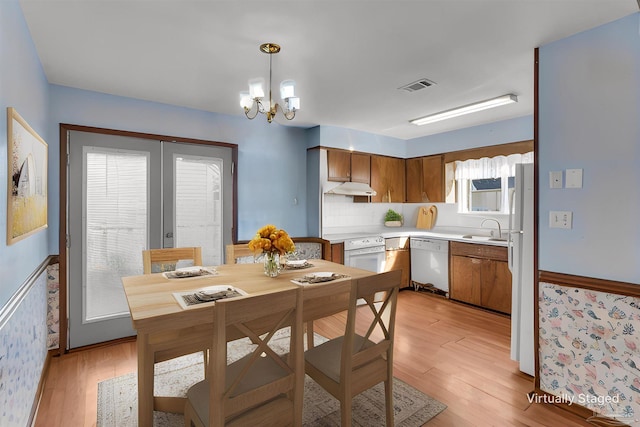 kitchen featuring white appliances, light wood-type flooring, sink, and decorative light fixtures