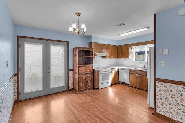 kitchen featuring white appliances, sink, decorative light fixtures, light hardwood / wood-style floors, and french doors