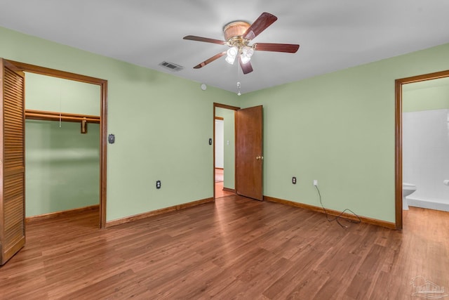 unfurnished bedroom with ceiling fan, ensuite bath, a closet, and hardwood / wood-style floors