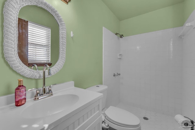 bathroom featuring vanity, a tile shower, and toilet