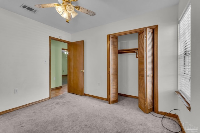 unfurnished bedroom featuring light carpet, a closet, and ceiling fan