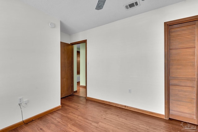 unfurnished bedroom with ceiling fan, light hardwood / wood-style floors, a textured ceiling, and a closet