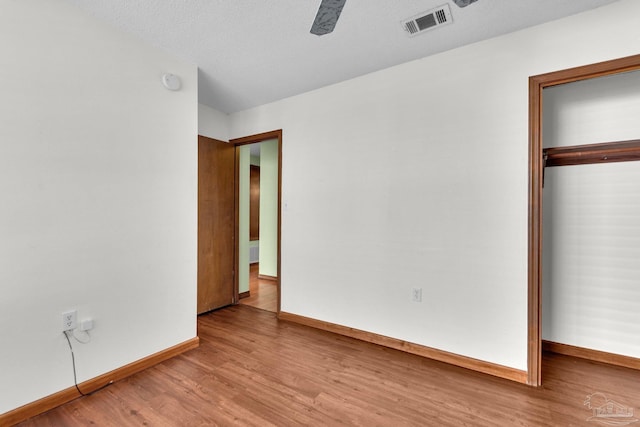 unfurnished bedroom featuring light wood-type flooring, a closet, a textured ceiling, and ceiling fan