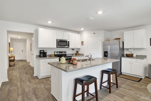 kitchen with stainless steel appliances, a kitchen island with sink, white cabinets, and sink