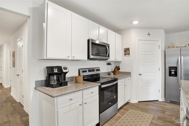 kitchen featuring light stone countertops, appliances with stainless steel finishes, dark hardwood / wood-style flooring, and white cabinetry