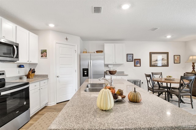 kitchen featuring an island with sink, white cabinets, appliances with stainless steel finishes, and sink