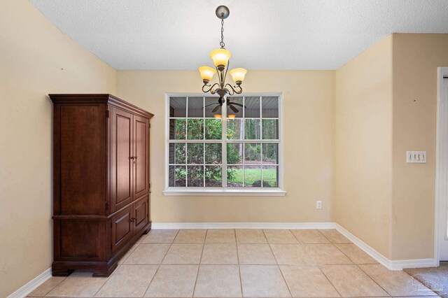 unfurnished dining area with a textured ceiling, ceiling fan with notable chandelier, and light tile patterned flooring