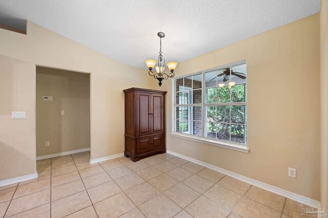 tiled spare room featuring a textured ceiling, ceiling fan with notable chandelier, and lofted ceiling