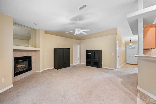 unfurnished living room featuring visible vents, light carpet, a tiled fireplace, lofted ceiling, and ceiling fan