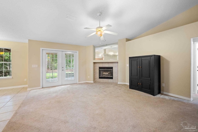 unfurnished living room featuring carpet, french doors, a wealth of natural light, and a tile fireplace