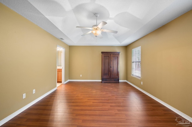 spare room featuring a raised ceiling, baseboards, dark wood-style flooring, and visible vents