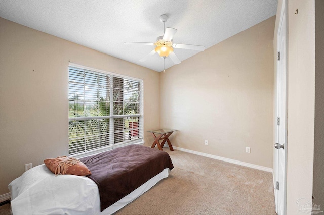 bedroom featuring baseboards, carpet, vaulted ceiling, a textured ceiling, and a ceiling fan