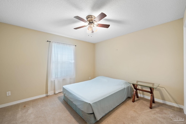 bedroom featuring light colored carpet, a textured ceiling, and baseboards