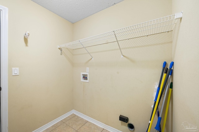 laundry room with a textured ceiling, light tile patterned floors, baseboards, hookup for a washing machine, and laundry area