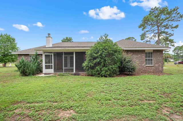 back of property with a lawn and a sunroom