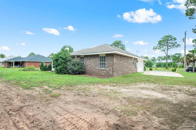 view of side of home featuring brick siding, an attached garage, concrete driveway, and a yard