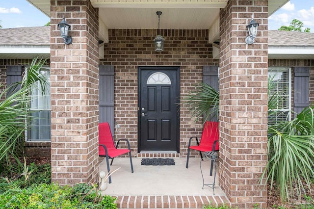 property entrance with brick siding and roof with shingles