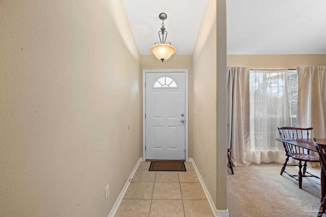 entryway with a textured ceiling and light colored carpet