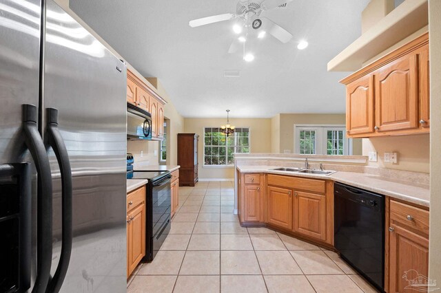 kitchen with pendant lighting, ceiling fan with notable chandelier, black appliances, sink, and light tile patterned flooring