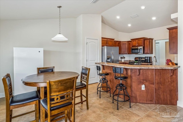 kitchen with pendant lighting, sink, appliances with stainless steel finishes, vaulted ceiling, and kitchen peninsula