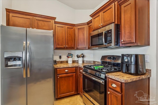 kitchen featuring appliances with stainless steel finishes, light tile patterned floors, and light stone counters