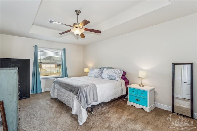 bedroom featuring dark carpet, a tray ceiling, and ceiling fan