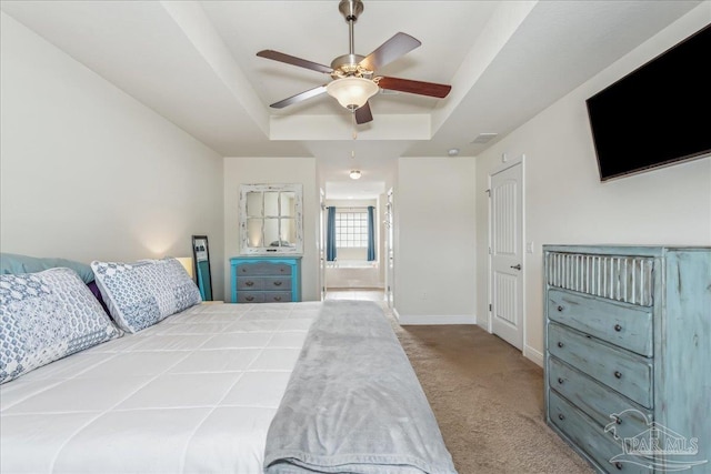 carpeted bedroom featuring ceiling fan, ensuite bath, and a raised ceiling