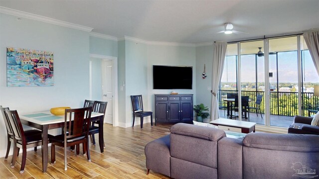 living area with a ceiling fan, light wood-type flooring, plenty of natural light, baseboards, and crown molding