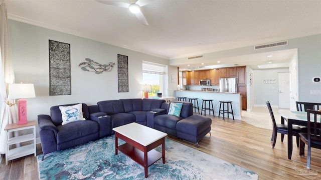 living area with light wood-type flooring, ornamental molding, ceiling fan, and recessed lighting