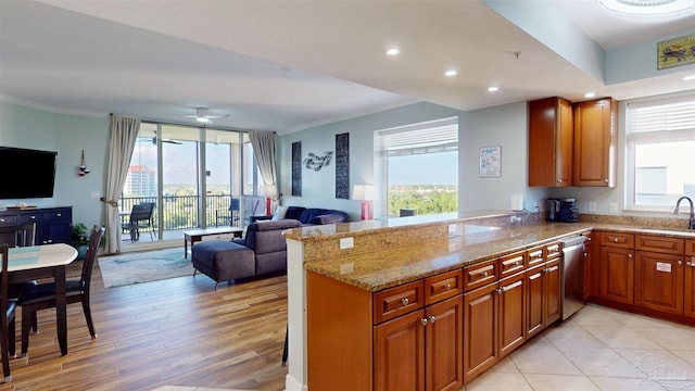 kitchen featuring open floor plan, a sink, ornamental molding, light stone countertops, and plenty of natural light