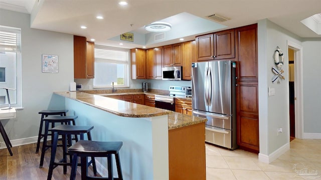 kitchen with stainless steel appliances, a peninsula, a sink, a kitchen breakfast bar, and recessed lighting