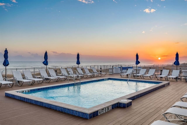 community pool with a deck with water view and fence