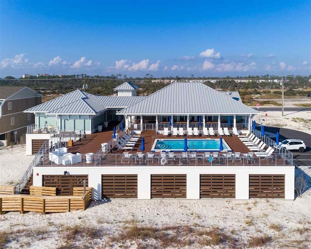 rear view of property with a community pool, an attached garage, metal roof, and fence