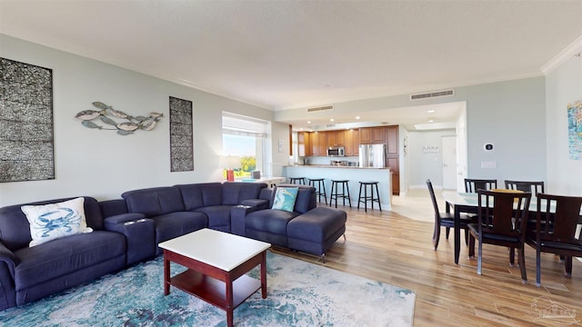 living area with crown molding and light wood finished floors