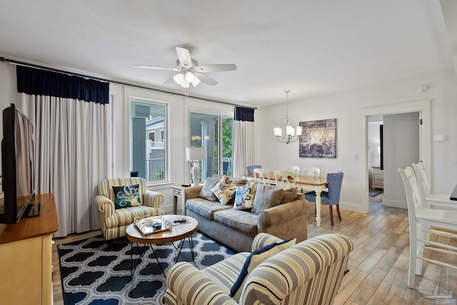 living room featuring ceiling fan with notable chandelier and light wood-type flooring