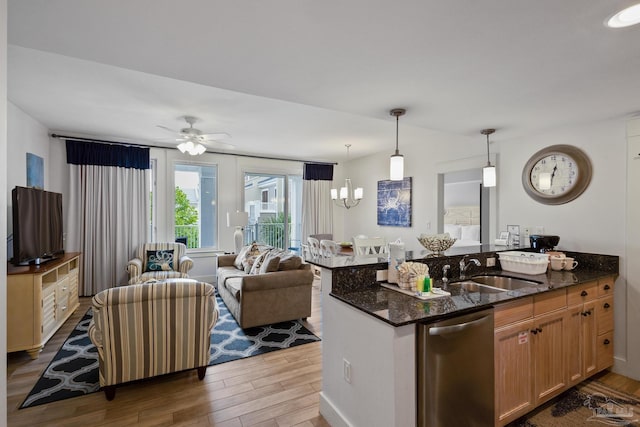 kitchen with dark stone countertops, stainless steel dishwasher, sink, and wood-type flooring