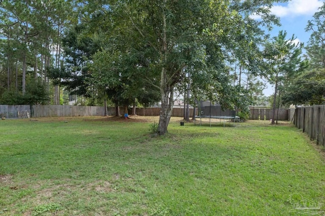 view of yard with a trampoline and a fenced backyard