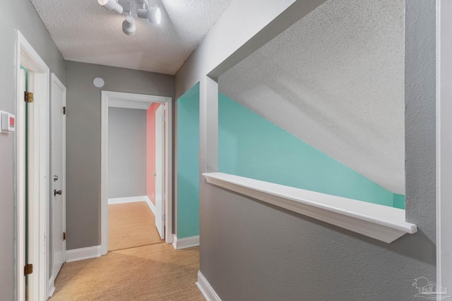 corridor featuring light carpet and a textured ceiling