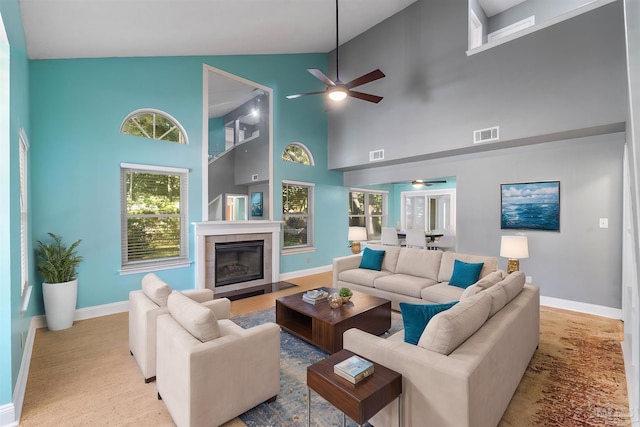 living room with a tile fireplace, high vaulted ceiling, and light hardwood / wood-style floors